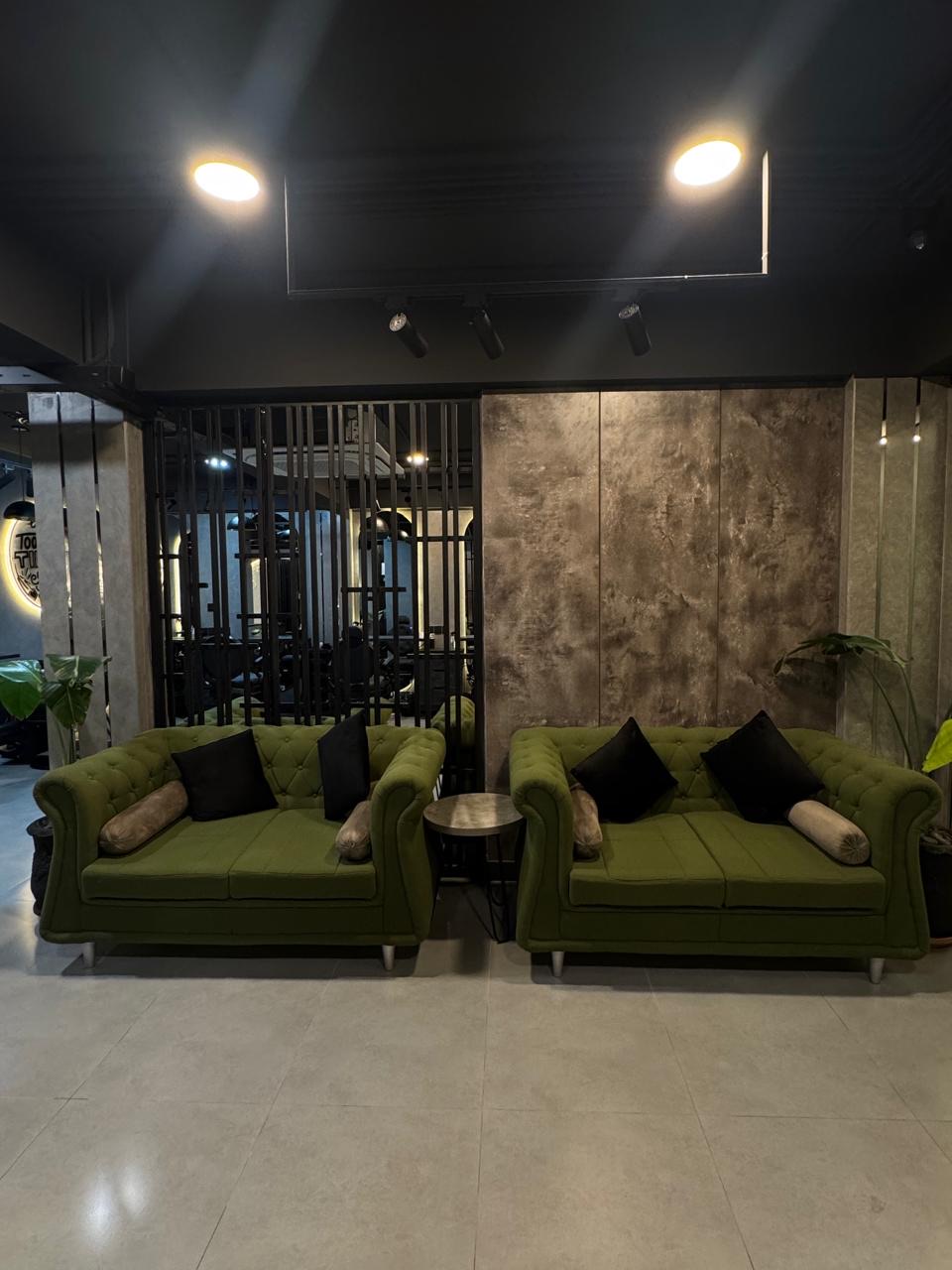 Two green velvet sofas in the guest lounge of The Man Redefined