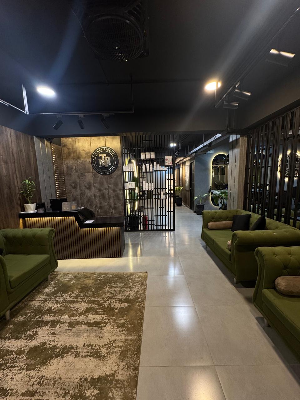 Reception and green velvet lounge seating inside The Man Redefined