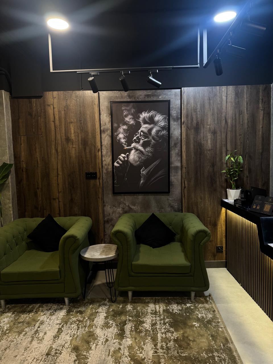 Waiting lounge with green velvet armchairs and a framed portrait at The Man Redefined